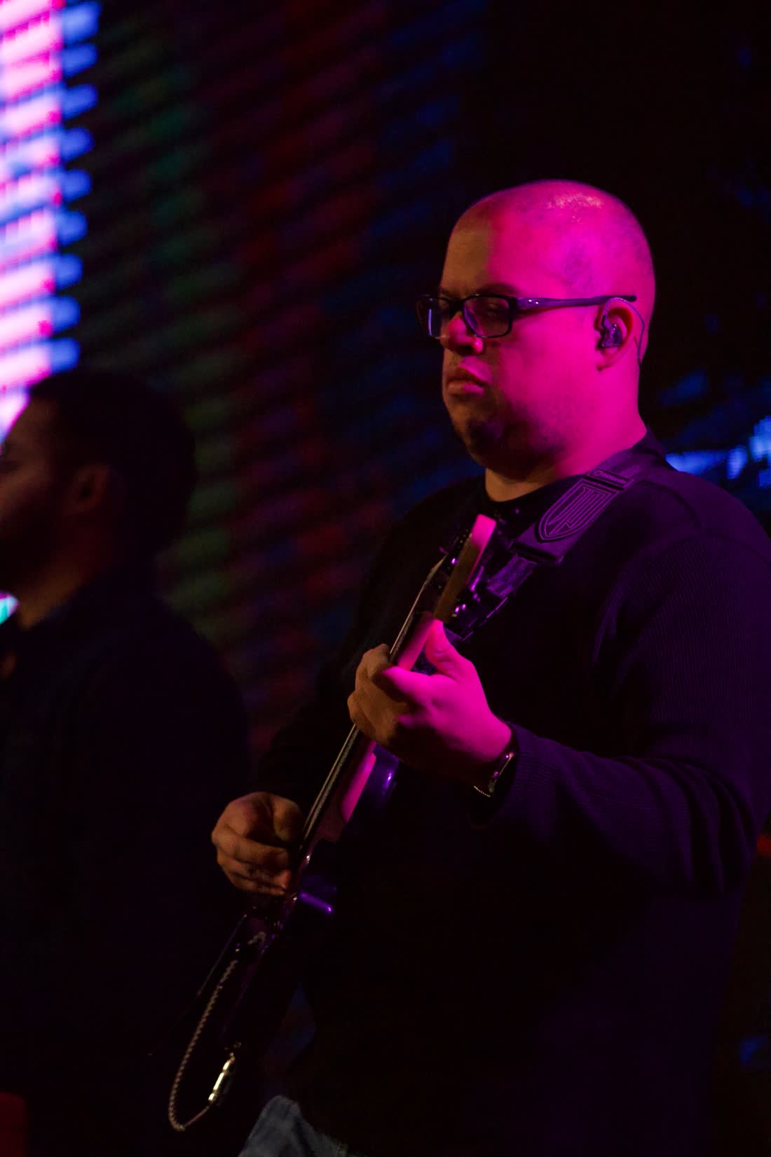 Frank Torres playing guitar under magenta stage light